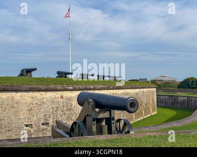 Una fila di storici cannoni di difesa costieri allinea i bastioni erbosi di Fort Macon, nella Carolina del Nord, con una bandiera americana Foto Stock