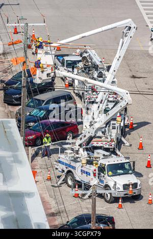 Miami Beach, Florida, uomini di servizio che riparano linee elettriche, camion con benna Altec, veicoli elettrici Pike, coni di sicurezza che segnano la zona di lavoro, uomini in elmetti u Foto Stock