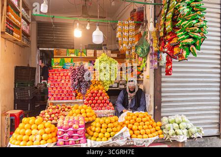 Distributore di frutta fresca che vende varietà di frutta di stagione nel vivace mercato di strada. Foto Stock
