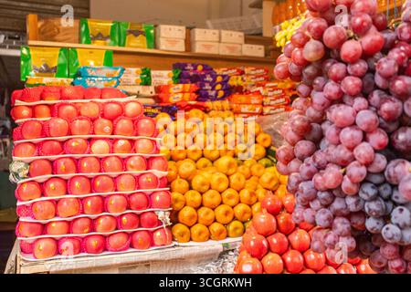 Bancarelle di frutta del mercato locale con coloratissima disposizione di agrumi e mele Foto Stock