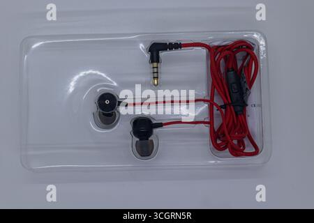 Auricolari rossi cablati su sfondo bianco con vista ravvicinata Foto Stock