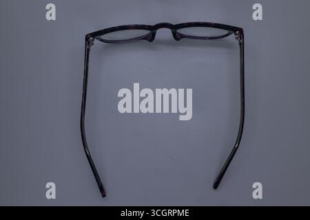Occhiali da lettura aperti su una superficie bianca semplice Foto Stock