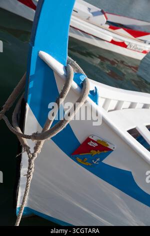 Una barca tradizionale in legno dipinto e corda sull'acqua Foto Stock