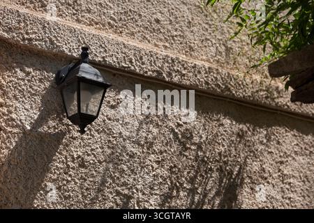 Una lanterna nera su un muro vicino a una pianta Foto Stock