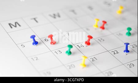 Pagina del calendario aziendale pianificazione degli impegni, gestione del tempo, scadenze e pianificazione degli eventi con molti push pin colorati sul calendario cartaceo mensile. Foto Stock