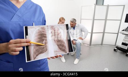Gli specialisti discutono la salute del paziente polmonare mentre mostrano un'immagine radiografica dettagliata in ambiente clinico medico. Dipartimento di Pulmonologia Foto Stock