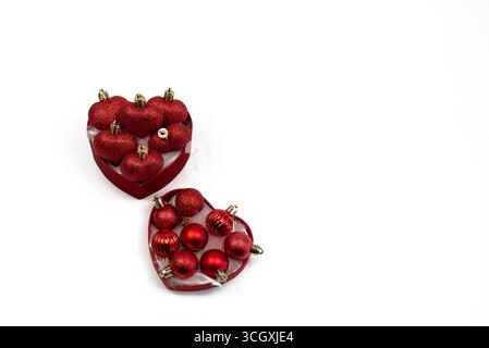 Scatola rossa con bulbi natalizi rossi assortiti su sfondo bianco. Lampadine rosse a forma di cuore e mini lampadine rosse assortite Foto Stock