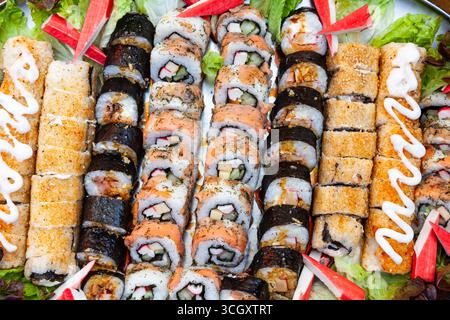 Una grande porzione su un vassoio di panini cotti e sushi di diversi tipi, vista dall'alto. Foto Stock