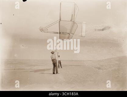 Vista laterale di Dan Tate, sinistra e Wilbur, destra, battenti 1902 glider come un aquilone. Foto Stock