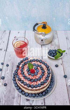 Tartine singole in velluto rosso: Base per torta in spugna in un anello di metallo, ripiena di mousse di mirtilli e crema Chantilly Foto Stock