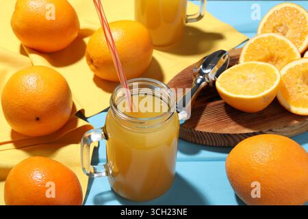 Succo d'arancia appena spremuto, frutta e centrifuga su un tavolo di legno blu, primo piano Foto Stock