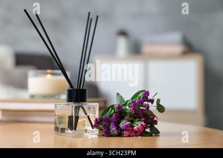 Diffusore di canne e fiori aromatici su tavola di legno, primo piano Foto Stock