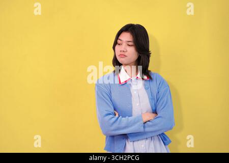 giovane che posa con un maglione blu su uno sfondo giallo brillante Foto Stock