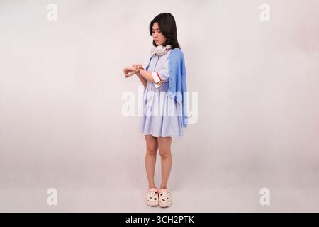 giovane donna casual che controlla il tempo indossando le cuffie in una configurazione minimalista Foto Stock