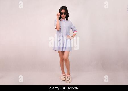 giovane donna elegante che indossa con sicurezza un abito casual e occhiali da sole Foto Stock