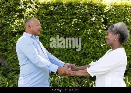 Coppia senior che si tiene per mano all'aperto, sorridendo e godendosi la compagnia reciproca Foto Stock