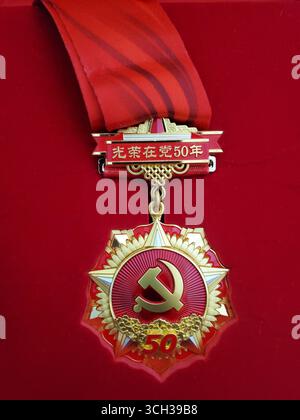 Medaglia d'Onore di 50 anni del Partito Comunista Cinese, nastro rosso con insegne di martello e falce Foto Stock