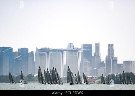 Didascalia: Flotta di yacht a vela che gareggiano in regata con lo skyline di Singapore Marina Bay Sands sullo sfondo - concetto di sport acquatici di lusso Foto Stock