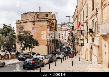La Valletta, Malta - 10 aprile 2025: Vista sulla strada con edifici storici in pietra calcarea e balconi tradizionali Foto Stock