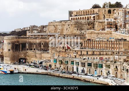La Valletta, Malta - 10 aprile 2025: Vista dello storico lungomare e delle fortificazioni della Valletta, con traghetti ormeggiati e navi da crociera nel Grand Harbo Foto Stock