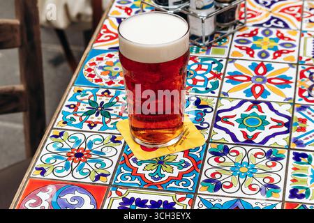 Una pinta di birra su un tavolo di piastrelle di ceramica colorata a la Valletta, Malta Foto Stock