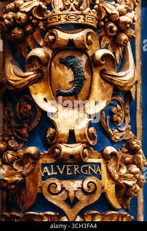 La Valletta, Malta – 10 aprile 2025: Scudo barocco dorato con delfino coronato e iscrizione “ALVERGNA”, che rappresenta la Langue dell’Alvernia del coltello Foto Stock