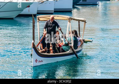 Senglea, Malta - 10 aprile 2025: Taxi d'acqua tradizionale dgħajsa che trasporta i turisti attraverso il Grand Harbour tra Senglea e Birgu Foto Stock