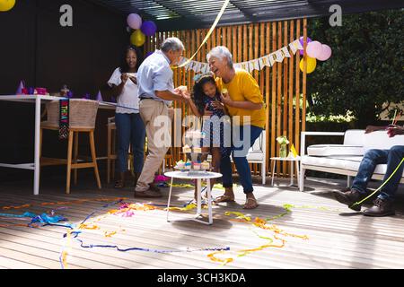 Alla festa, festeggiando il compleanno in giardino, la famiglia che balla con il bambino, i nonni sorridono Foto Stock