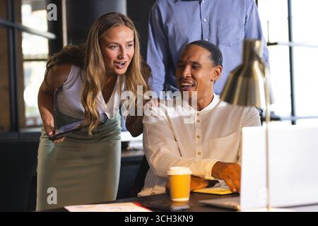 Colleghi diversi che discutono di progetti alla scrivania dell'ufficio, sorridono e collaborano su idee Foto Stock