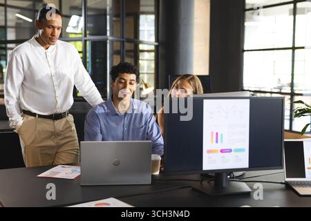 Team aziendale che collabora al progetto con notebook e grafici in uffici moderni Foto Stock