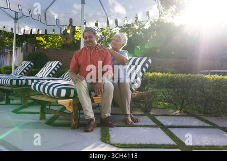 Coppie anziane e diverse che si rilassano sui lettini e si godono una giornata di sole in giardino Foto Stock
