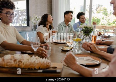 Al piccolo ricevimento di nozze informale, gli amici ridono e parlano mentre tengono un drink, a casa Foto Stock