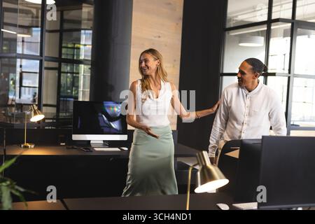 Colleghi in un ufficio moderno che discutono del progetto con entusiasmo e collaborazione Foto Stock