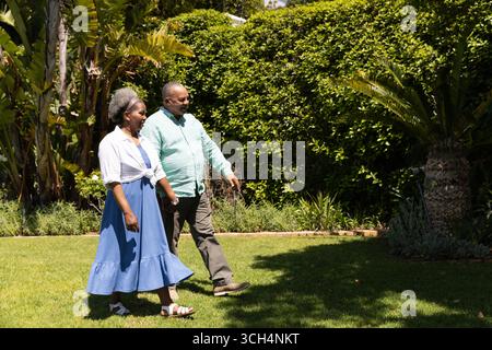 La coppia senior cammina in giardino, si gode una giornata di sole e la compagnia reciproca Foto Stock