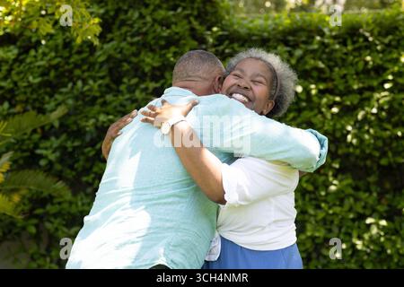Coppia senior che abbraccia gioiosamente in giardino, condividendo momenti caldi e felici Foto Stock
