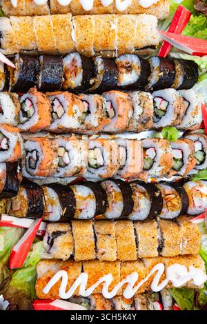 Una grande porzione su un vassoio di panini cotti e sushi di diversi tipi, vista dall'alto. Foto Stock