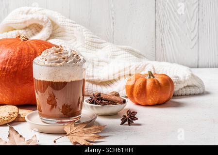Tazza di caffè con zucca Spice latte con zucche, foglie di mela, biscotti e plaid di lana. Bevanda a base di caffè di stagione con panna montata, spazio per fotocopie. Foto Stock