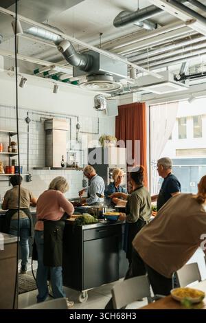 Corso di cucina senior con chef in una cucina commerciale molto affollata Foto Stock