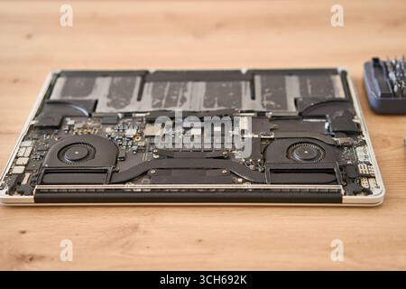 Computer portatile smontato insieme a vari utensili posizionati ordinatamente su una superficie in legno per le riparazioni Foto Stock