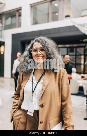 Ritratto di una donna d'affari sorridente in piedi con la mano in tasca nel centro congressi Foto Stock