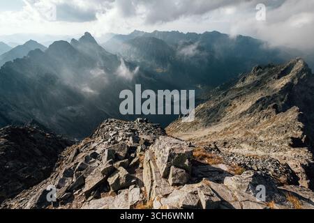 Nuvole nebbiose che si innalzano sul lago Morskie Oko la mattina presto nella catena montuosa degli alti Tatra con luci e ombre incredibili. Vista del picco Rysy 2499 m. Foto Stock