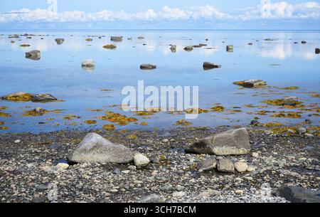 Tranquilla costa rocciosa con calmi riflessi del Mar bianco e del cielo blu e pietre in acqua in Carelia, concetto di natura, sfondo e paesaggio Foto Stock