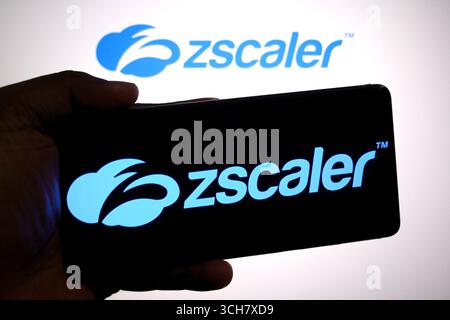 In questa immagine, il logo Zscaler viene visualizzato su uno smartphone e sullo sfondo. Foto Stock