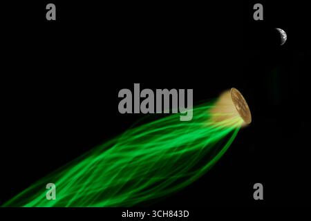 Un Bitcoin fisico che irradia una luce dorata con una dinamica striscia di energia verde, viaggiando attraverso lo spazio verso la luna. Un concetto per la rapida crescita Foto Stock