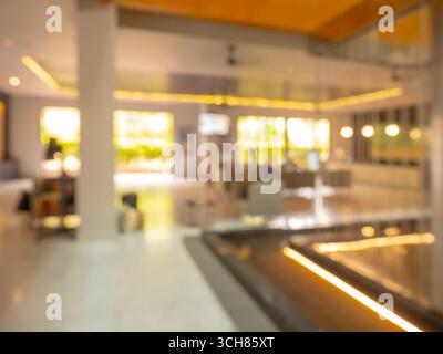 Sfondo sfocato della reception dell'hotel con luci calde e interni dal design moderno, adatto per pubblicità di viaggi, settore alberghiero, prenotazioni Foto Stock