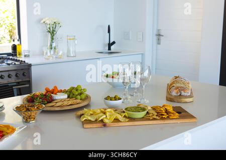 Stuzzichini, frutta fresca e bicchieri da vino, elegante bancone da cucina per festeggiare Foto Stock