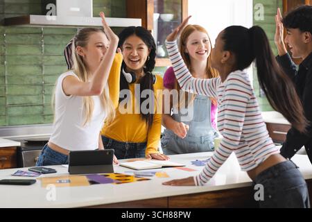 Teen Friends che si esibiscono in cucina e celebrano il successo con sorrisi gioiosi Foto Stock