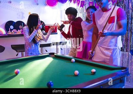 Ragazzi che festeggiano a casa, giocano a biliardo e si godono un'atmosfera vivace Foto Stock