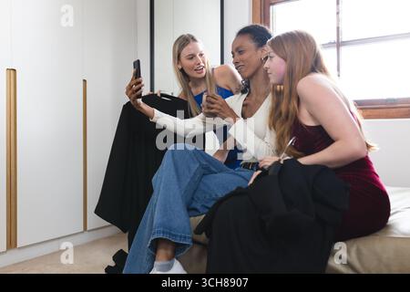 Ragazze adolescenti sedute insieme a fare selfie e ridere a casa Foto Stock