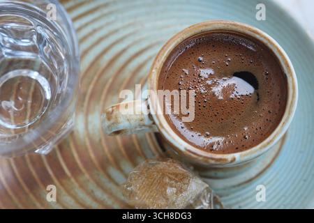 tazza di caffè turco su un piatto di ceramica vicino all'acqua Foto Stock